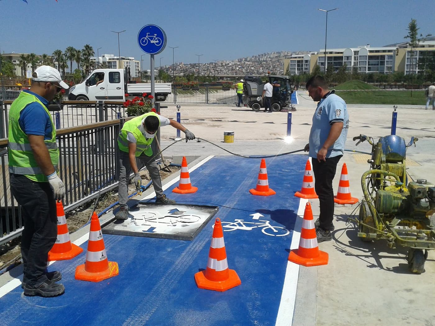 Line marking crew in hi-vis setting up cones and a stencil around a work area before painting